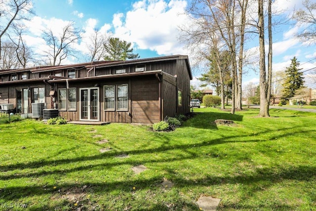 back of property with a yard, central air condition unit, and french doors