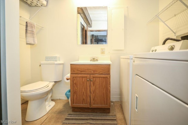 bathroom with washing machine and clothes dryer, vanity, tile patterned floors, toilet, and baseboards