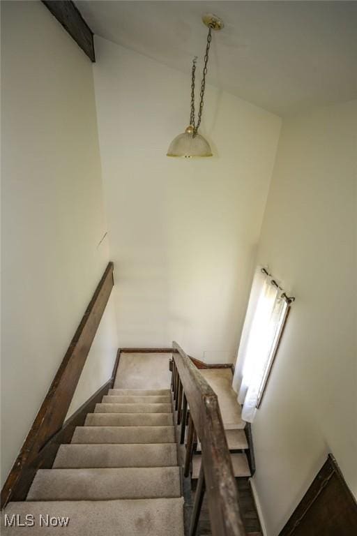 stairs with baseboards, vaulted ceiling with beams, and carpet