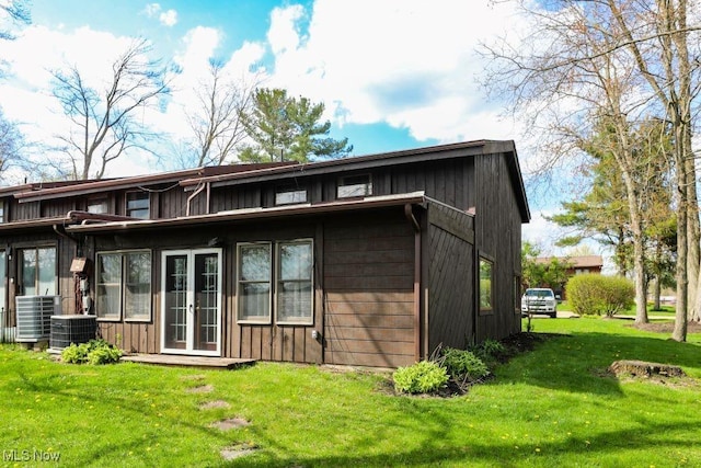 back of property with central air condition unit and a lawn