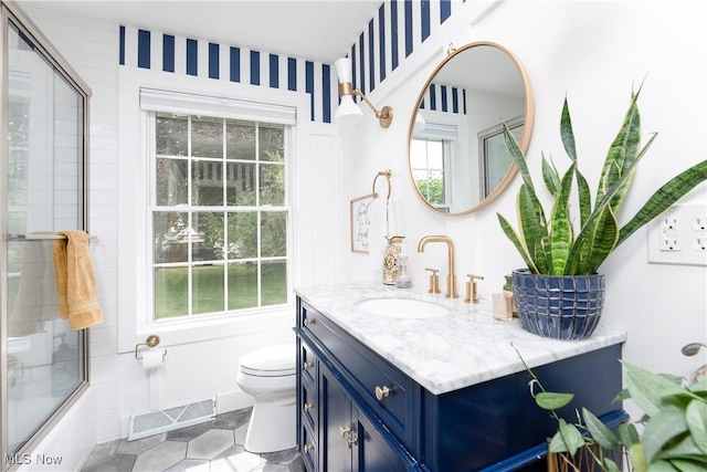 full bathroom with bath / shower combo with glass door, visible vents, toilet, vanity, and tile patterned flooring