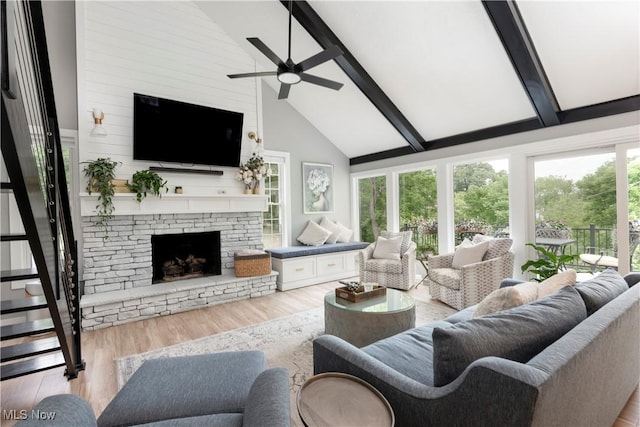 living area featuring beamed ceiling, a fireplace, high vaulted ceiling, a ceiling fan, and wood finished floors