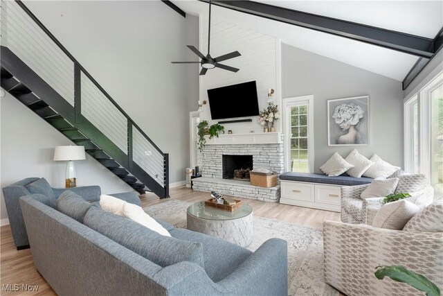 living room with ceiling fan, stairway, beam ceiling, and wood finished floors
