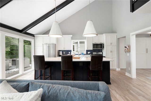 kitchen featuring appliances with stainless steel finishes, light countertops, white cabinets, backsplash, and high vaulted ceiling