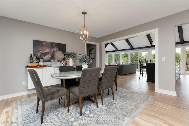dining area with baseboards, lofted ceiling with beams, an inviting chandelier, and light wood-style floors