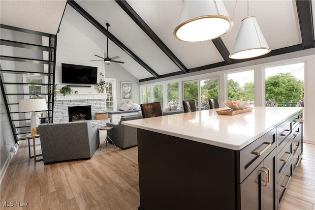 kitchen featuring beamed ceiling, ceiling fan, a kitchen island, and light countertops
