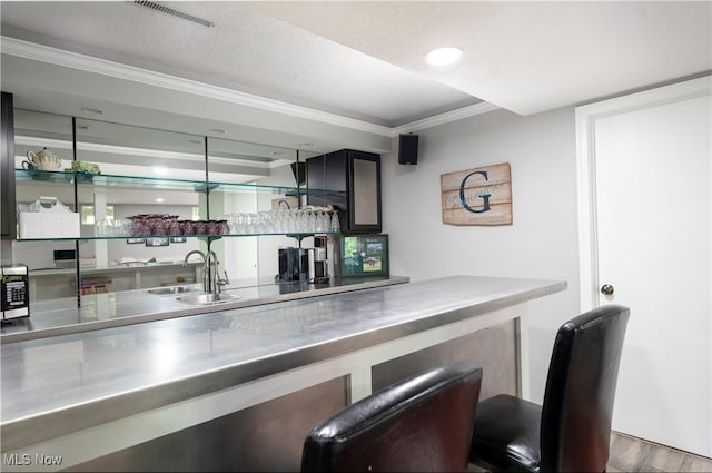 bar featuring stainless steel microwave, crown molding, wet bar, visible vents, and wood finished floors