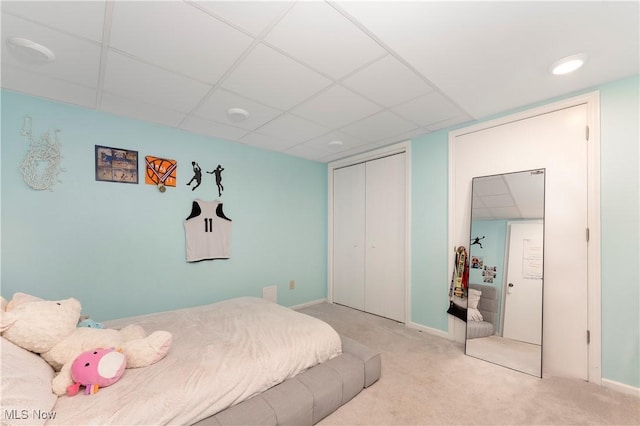 carpeted bedroom featuring baseboards, a closet, and a drop ceiling