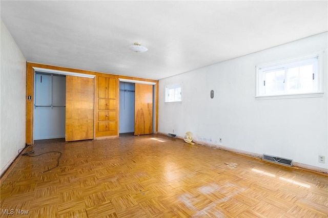 unfurnished bedroom featuring visible vents, multiple closets, and baseboards