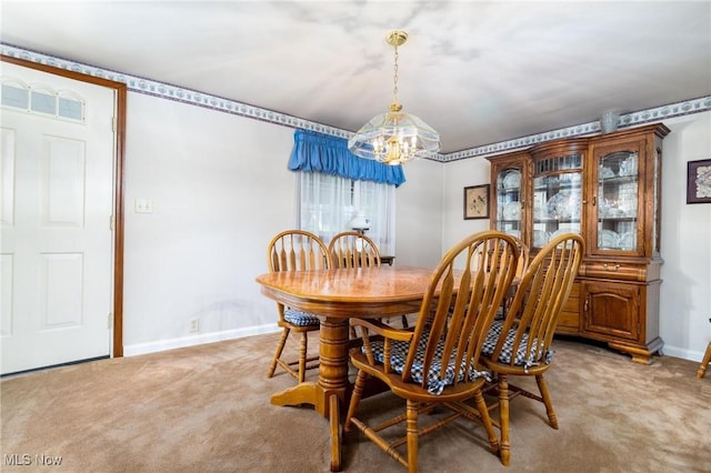 dining area featuring light carpet, a chandelier, and baseboards