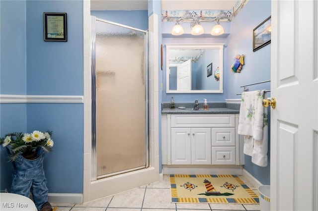 full bath with baseboards, a stall shower, tile patterned flooring, and vanity