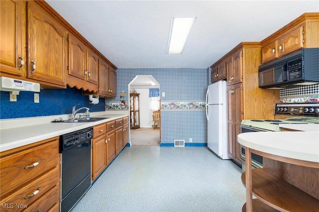 kitchen with black appliances, brown cabinets, light countertops, and a sink