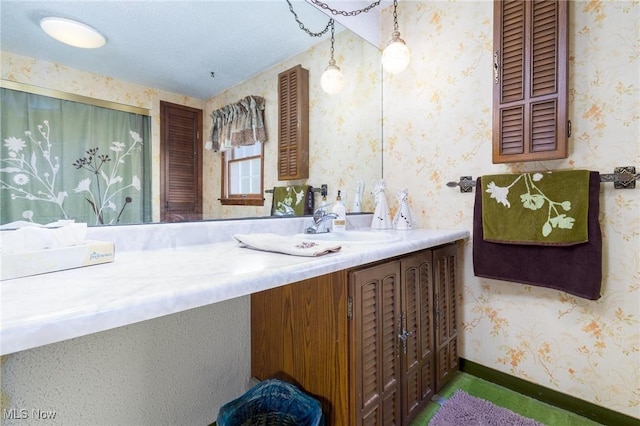 bathroom with vanity, wallpapered walls, and baseboards