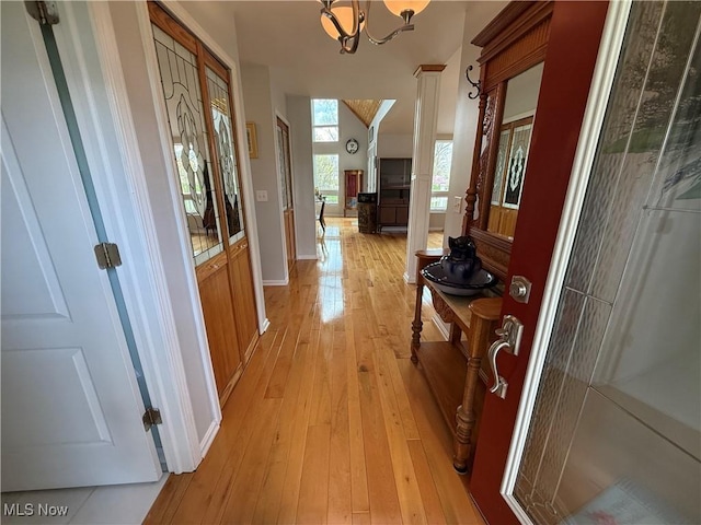 hall with baseboards, a chandelier, and light wood-style flooring