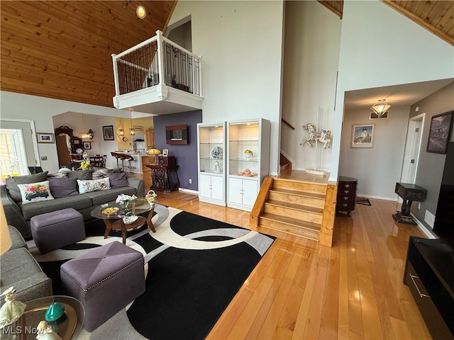 living room featuring wooden ceiling, stairway, high vaulted ceiling, baseboards, and hardwood / wood-style flooring