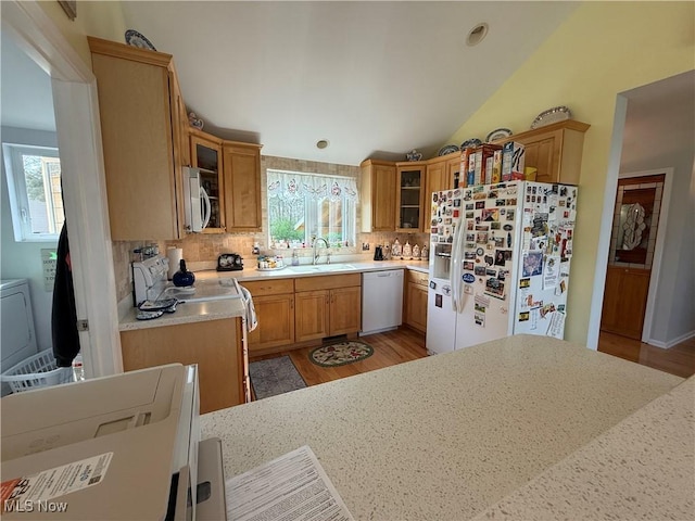 kitchen with a healthy amount of sunlight, white appliances, backsplash, and a sink