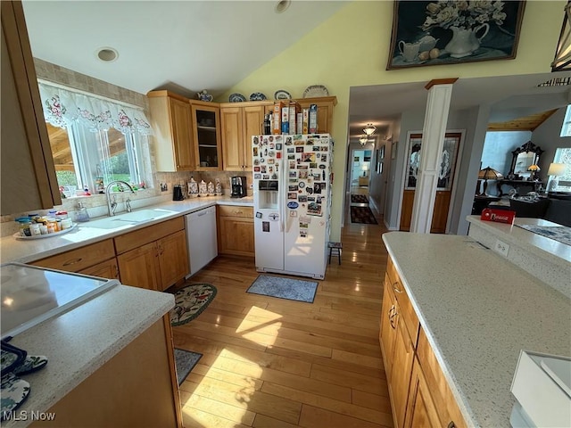 kitchen featuring light wood finished floors, a sink, tasteful backsplash, white appliances, and lofted ceiling