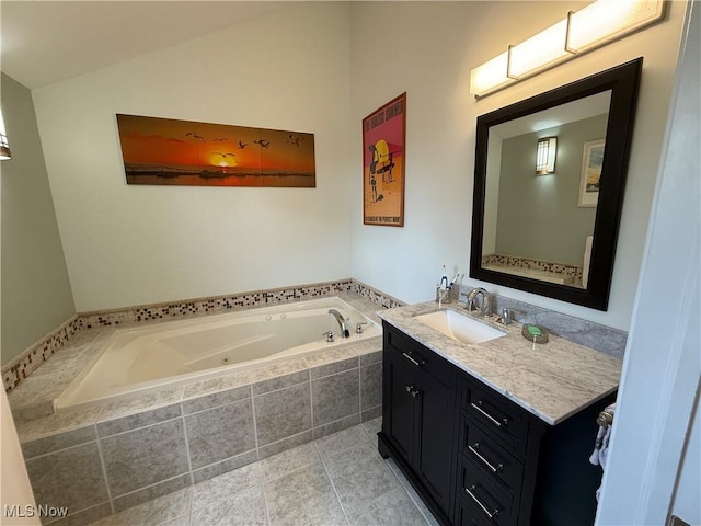 bathroom featuring a tub with jets, vanity, tile patterned floors, and lofted ceiling