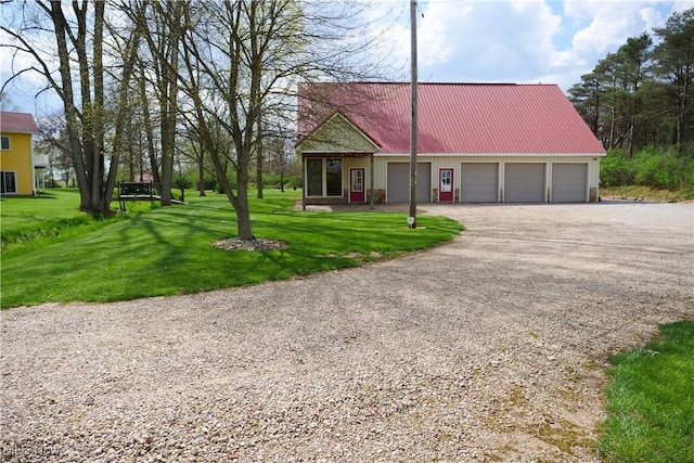 view of front of home featuring metal roof, a front lawn, driveway, and a garage