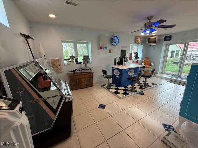 interior space featuring ceiling fan, light tile patterned floors, visible vents, and a healthy amount of sunlight