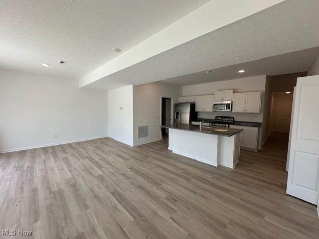 414 Honeycrisp Dr NE, Louisville, OH 44641 - kitchen featuring stainless steel appliances, dark countertops, white cabinetry, open floor plan, and light wood finished floors