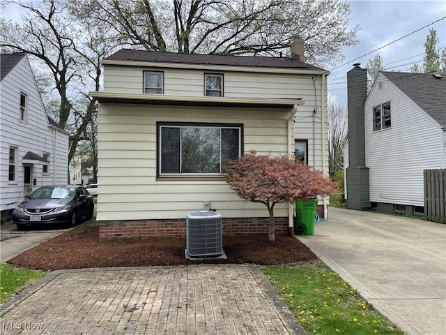 view of front of home with a chimney and central air condition unit