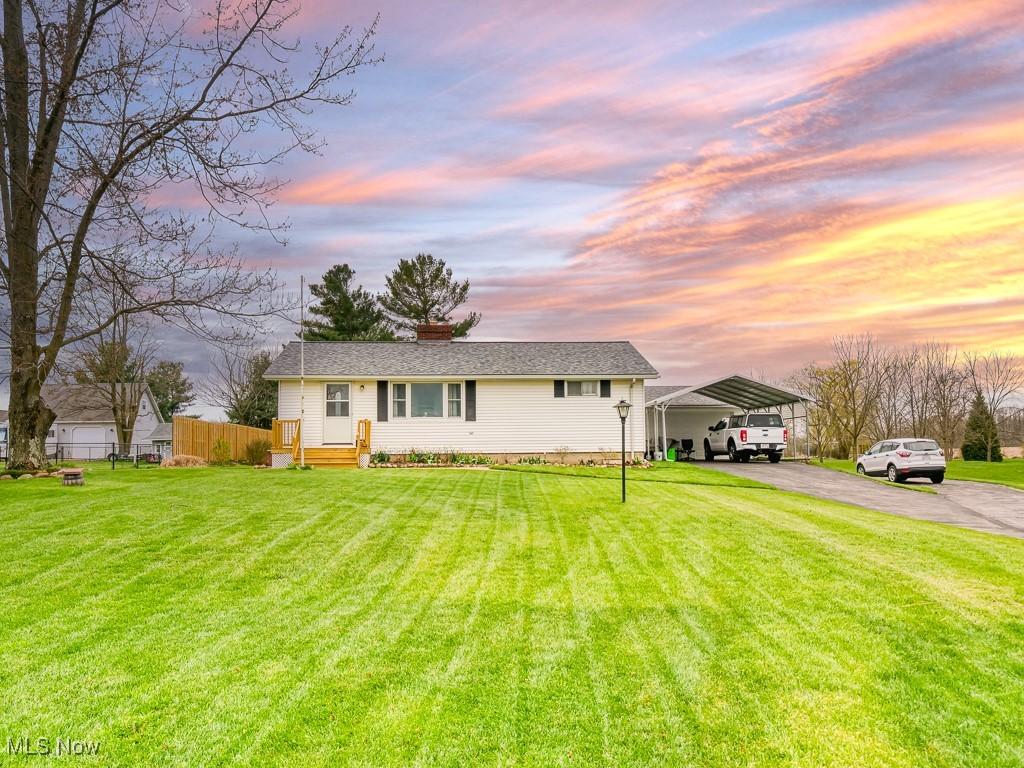 view of front facade featuring fence, a carport, a front lawn, and driveway