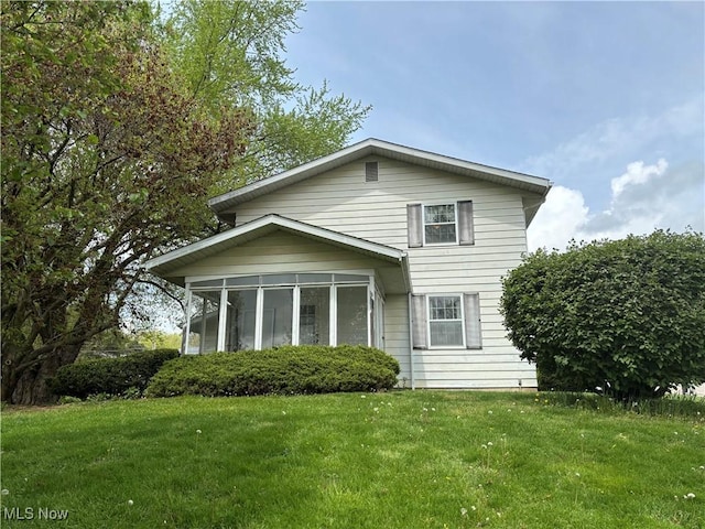 back of house featuring a lawn and a sunroom