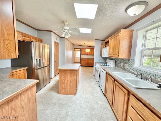 kitchen with a textured ceiling, a sink, a center island, white appliances, and a skylight