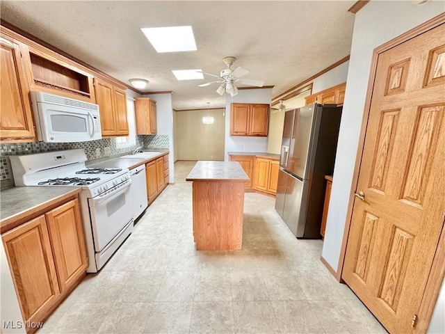 kitchen with ceiling fan, tasteful backsplash, a center island, white appliances, and a skylight