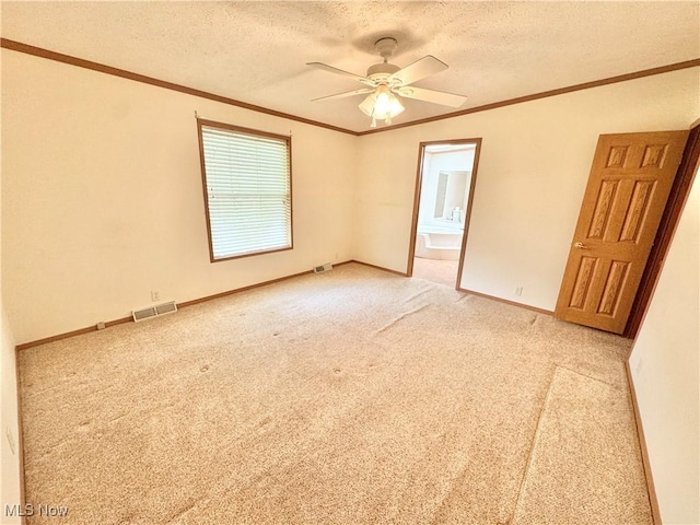 spare room featuring a textured ceiling, visible vents, light colored carpet, and a ceiling fan