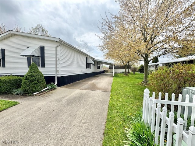 view of home's exterior with fence, concrete driveway, a yard, and an attached carport