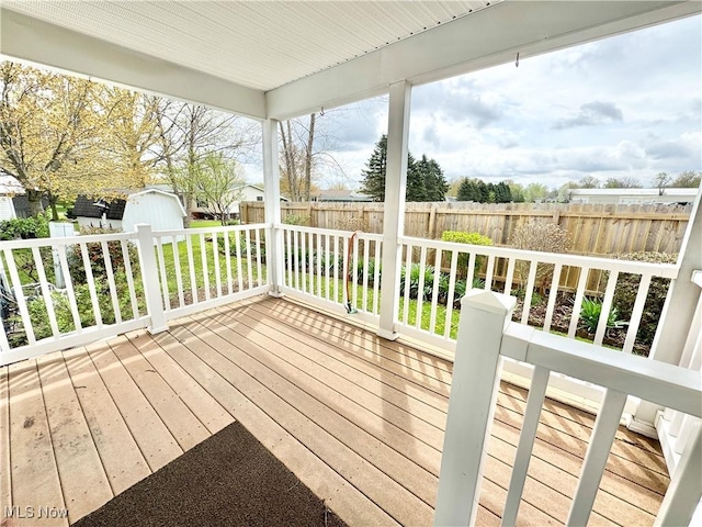 wooden terrace featuring an outbuilding, a storage shed, and fence