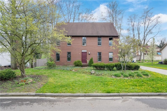 colonial home with fence and a front lawn