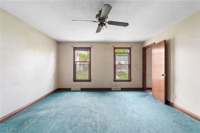 carpeted empty room featuring visible vents, a ceiling fan, and baseboards