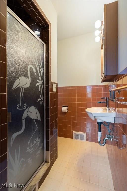 bathroom with tile walls, visible vents, a stall shower, and wainscoting