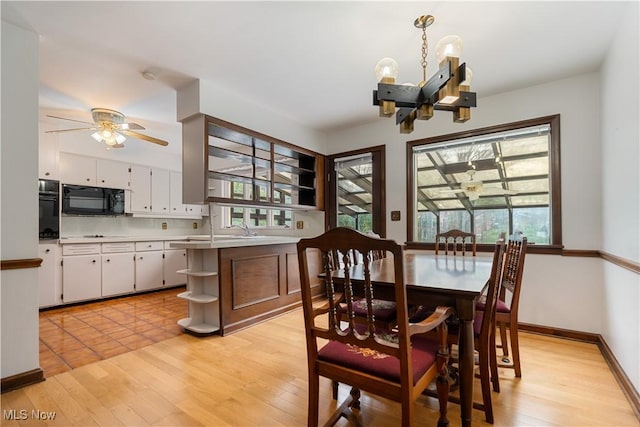 dining area featuring ceiling fan with notable chandelier, baseboards, a wealth of natural light, and light wood-style floors