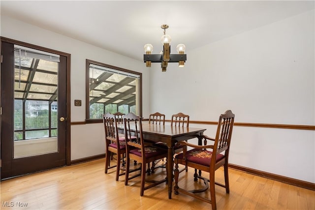 dining space featuring baseboards, an inviting chandelier, and light wood-style floors