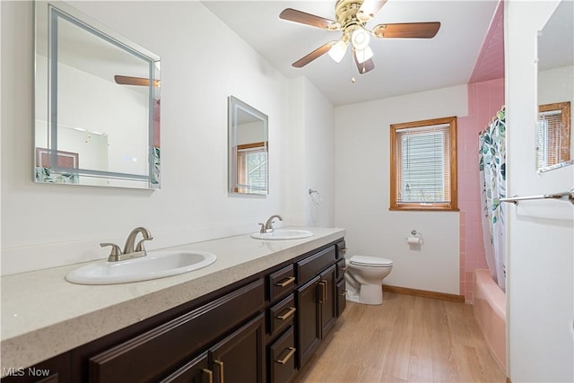 full bath with wood finished floors, toilet, double vanity, and a sink