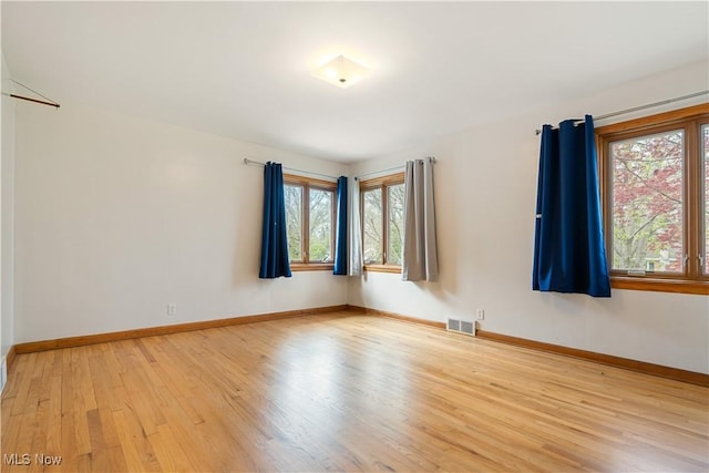 unfurnished room with plenty of natural light, visible vents, baseboards, and light wood-type flooring