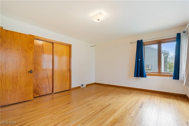 unfurnished bedroom featuring a closet, visible vents, baseboards, and light wood-type flooring