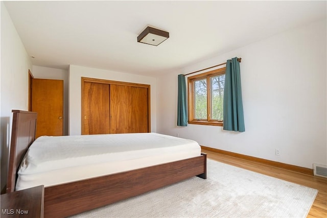 bedroom with wood finished floors, baseboards, and a closet