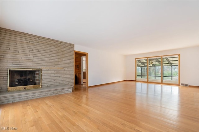 unfurnished living room featuring visible vents, baseboards, wood finished floors, and a fireplace