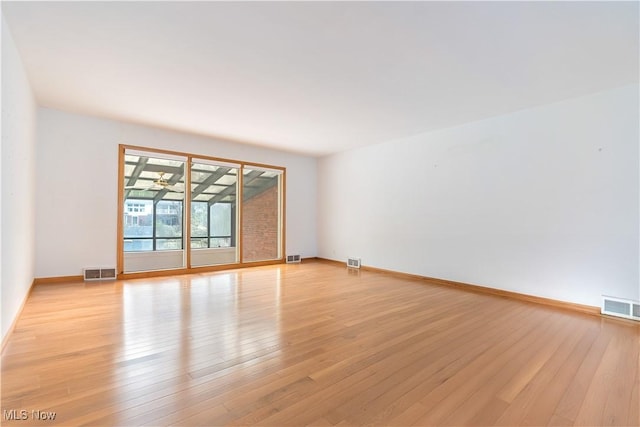 spare room featuring baseboards, visible vents, and light wood-style floors