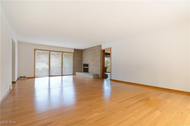 unfurnished living room with light wood finished floors, visible vents, baseboards, and a fireplace