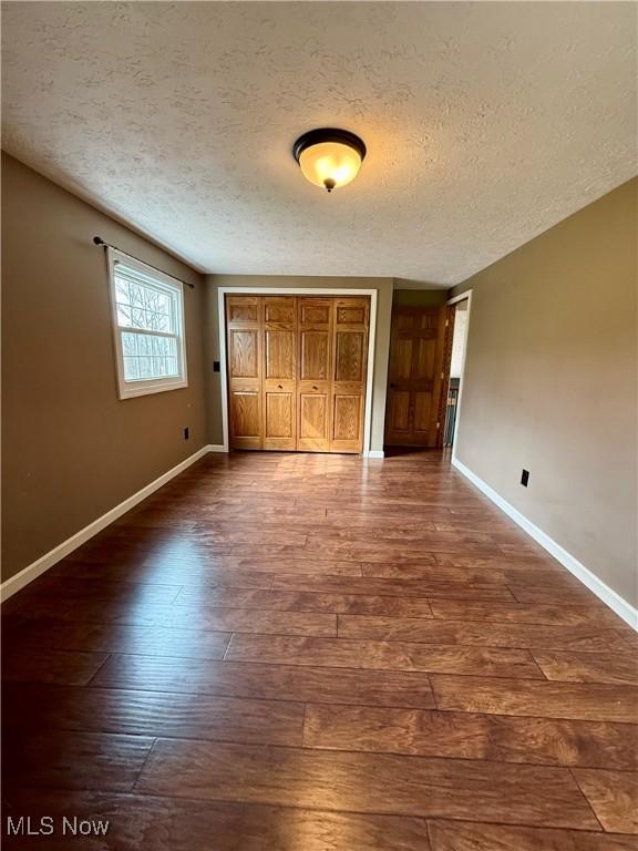 83 Oneida Trl, Malvern, OH 44644 - unfurnished bedroom featuring a closet, a textured ceiling, baseboards, and dark wood finished floors