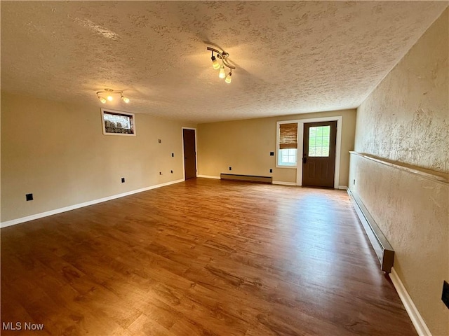83 Oneida Trl, Malvern, OH 44644 - unfurnished room featuring a textured ceiling, wood finished floors, a baseboard heating unit, and baseboards