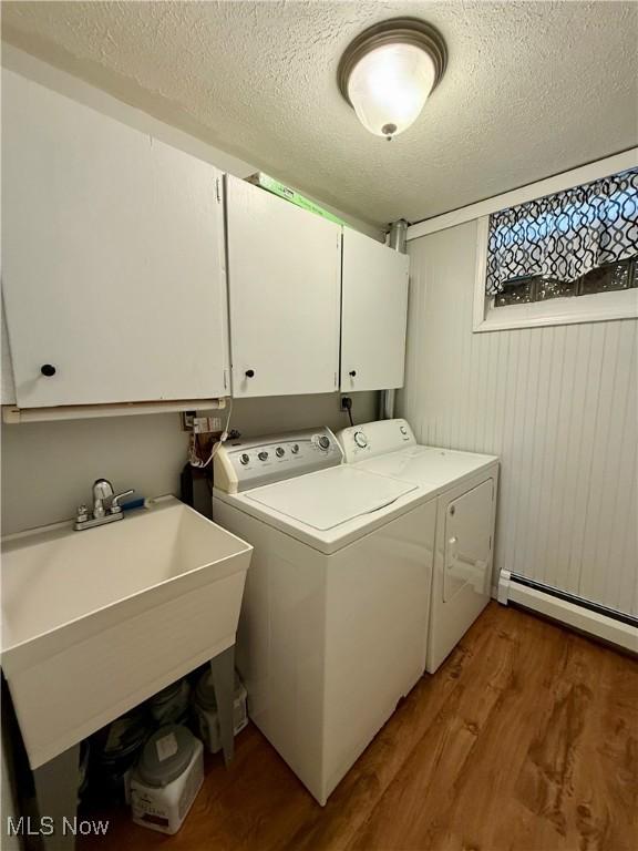 83 Oneida Trl, Malvern, OH 44644 - washroom featuring wood finished floors, separate washer and dryer, a baseboard heating unit, cabinet space, and a textured ceiling