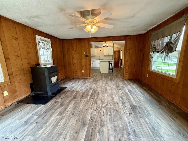 83 Oneida Trl, Malvern, OH 44644 - unfurnished living room with a wood stove, wood finished floors, and plenty of natural light