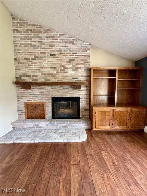 83 Oneida Trl, Malvern, OH 44644 - unfurnished living room featuring lofted ceiling, a textured ceiling, and hardwood / wood-style flooring